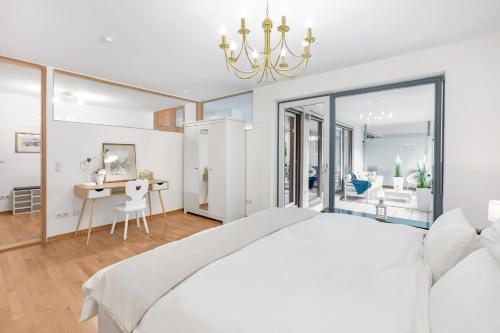 a white bedroom with a large bed and a desk at Zwei Zimmer Wohnung im Stadtzentrum mit Tiefgaragenplatz in Munich