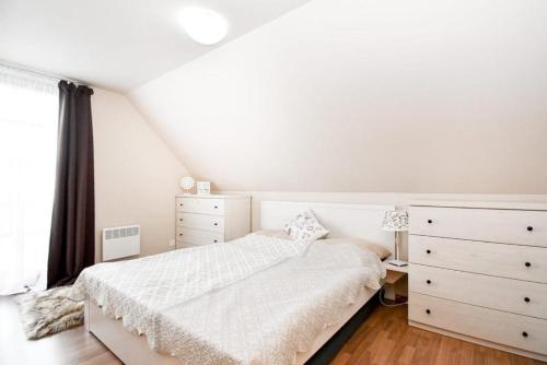 a white bedroom with a bed and a dresser at Apartmán s terasou in Říčky