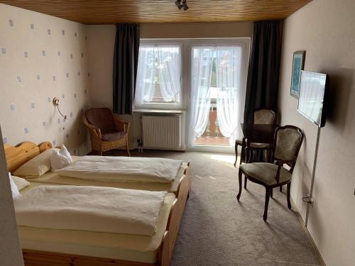 una camera con due letti e una sedia e finestre di Pension Florianhof a Schonach