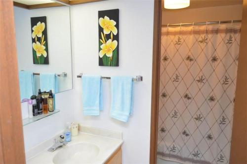 a bathroom with a sink and yellow flowers on the wall at Aikoloa Villas G201 Ocean Views in Waikoloa