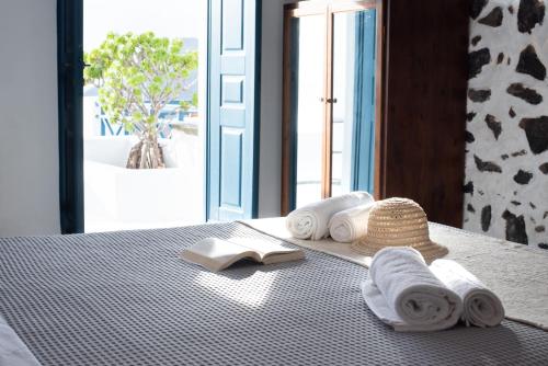 a bed with towels and a straw hat on it at DELION VIEW HOTEL in Fira