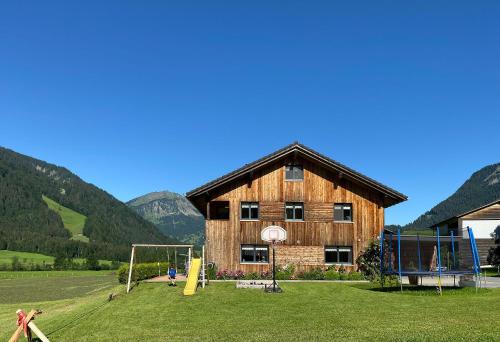 un edificio de madera con un parque infantil delante de él en Haus Helga, en Schoppernau