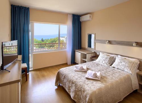 a hotel room with a bed with towels on it at Hotel Naslada in Balchik