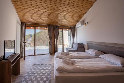 a bedroom with two beds and a flat screen tv at Вила БОЛЯРКА - РЕЛАКС in Glavatartsi