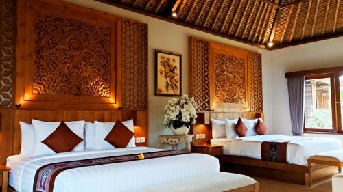 duas camas num quarto de hotel com lençóis brancos em Puri Andong Villa em Ubud