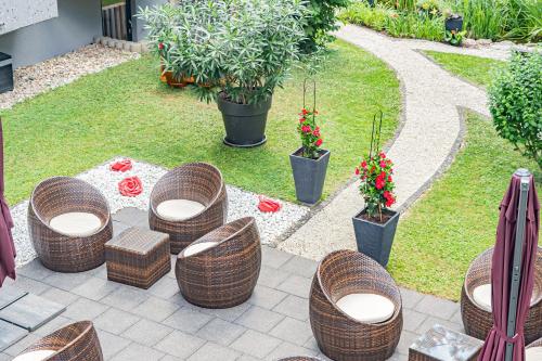 a patio with wicker chairs and tables and plants at Parkhotel Sonnenberg in Eltville