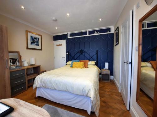 a bedroom with a large bed and a blue wall at Greenlands Guest House in Highbridge