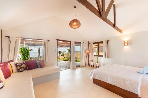 a bedroom with a bed and a couch at Rare Beachfront Villa - 2BR - 6 Pax Private Pool on Tuason Surf Spot in General Luna