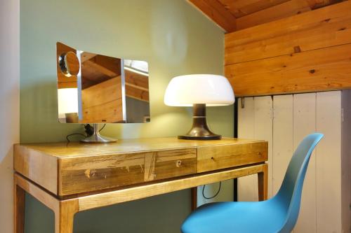 escritorio con espejo y silla azul en Apartments DA LA VEDLA Flats, en San Cassiano