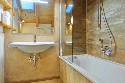 a bathroom with a sink and a bath tub at Apartments DA LA VEDLA Flats in San Cassiano