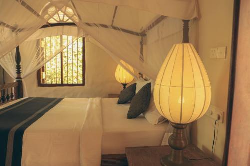 a bedroom with a bed with two lamps on it at Heenatigala Walawwa in Talpe