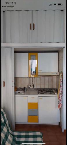 a small kitchen with white cabinets and yellow accents at San Salvo Marina Bilocale in Marina di Montenero