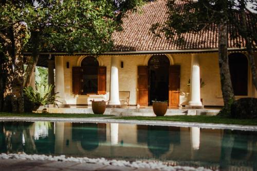 a house with a swimming pool in front of it at Pedlar's Manor in Talpe