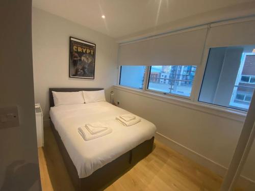 a bedroom with a bed with two towels on it at 90s RETRO 1Bed Studio Apartment Wembley Park London Private GYM & CINEMA & Netflix Perfect for Solo & Coupled Travellers in London