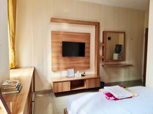 um quarto de hotel com uma cama e uma televisão de ecrã plano em 37 Guesthouse em Jakarta