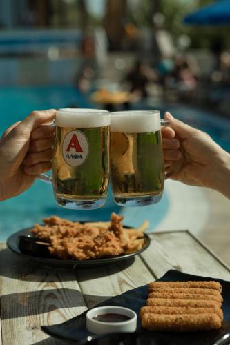 two people holding glasses of beer and a plate of food at Frank Apartments in Amoudara Herakliou