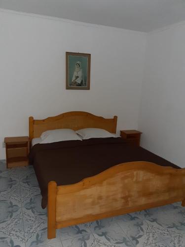 a bedroom with a wooden bed and a picture on the wall at Vila Margaritar in Eforie Sud