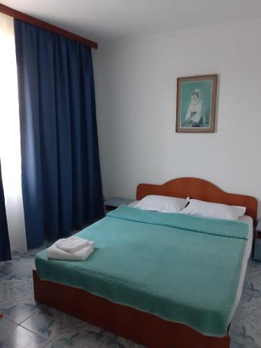 Schlafzimmer mit einem großen Bett und blauen Vorhängen in der Unterkunft Vila Margaritar in Eforie Sud