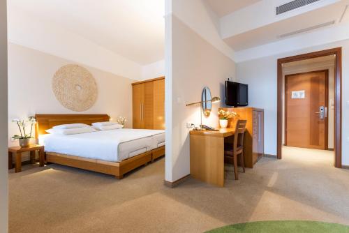 Dormitorio con cama, escritorio y TV en Hotel Livada Prestige - Terme 3000 - Sava Hotels & Resorts, en Moravske Toplice