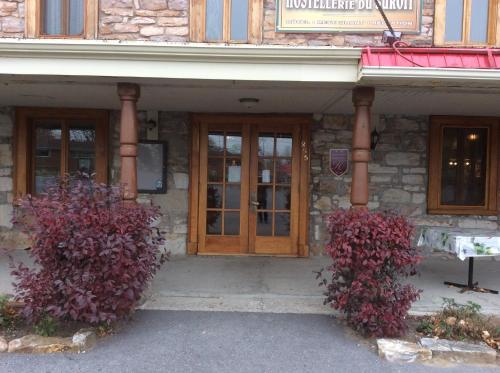 a building with two bushes in front of a door at Hostellerie du Suroît in Beauharnois