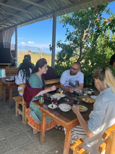 un grupo de personas sentadas en una mesa comiendo comida en Guest house and yurt camp "Aktan", en Bokonbayevo