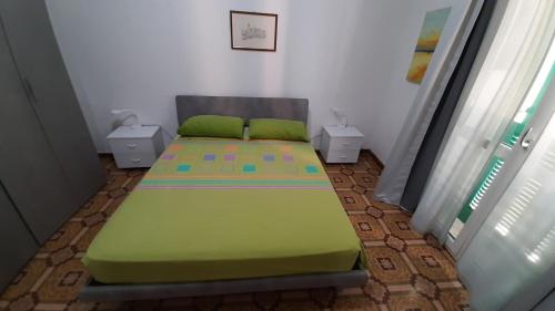 a green bed in a room with two tables at Appartamento Indipendenza - Tropea centralissimo in Tropea