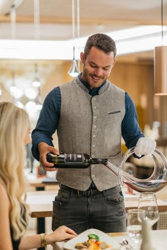 a man preparing food in a kitchen with a woman at Alpinhotel Berghaus spa in Tux