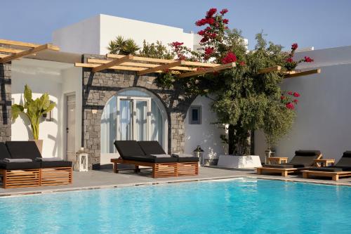 a pool with chaise lounge chairs and a swimming pool at Kalisti Hotel & Suites in Fira