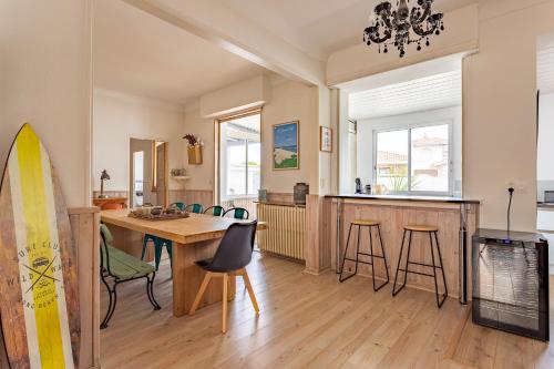 una cucina e una sala da pranzo con un tavolo e una tavola da surf di Villa à 2 pas de la plage ad Arcachon