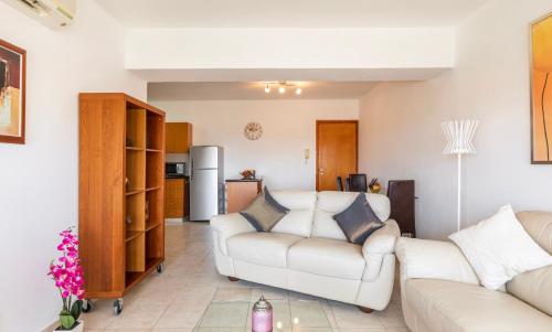 a living room with two white couches and a kitchen at Mediterranean dream in Voroklini