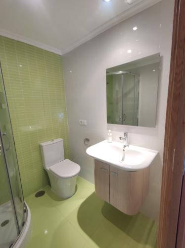 W łazience znajduje się umywalka, toaleta i lustro. w obiekcie Apartamento playa Cabodeiro, en A Illa De Arousa w mieście Isla de Arosa