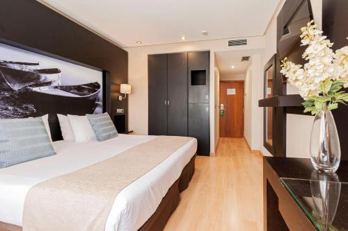 a hotel room with a bed and a vase of flowers at Oh Nice Ulises Ceuta in Ceuta