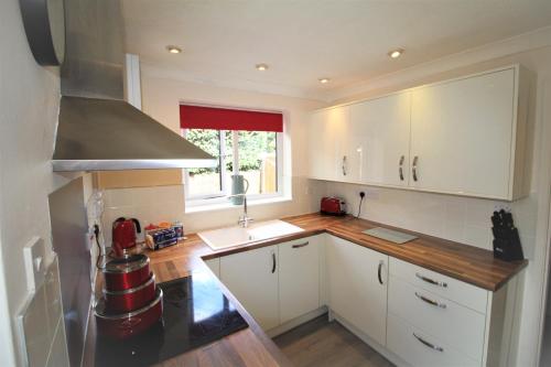 a kitchen with white cabinets and a sink at 3 Bed House - Garden & Parking - Quiet Cul De Sac in Doncaster