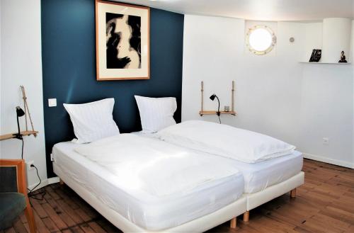 a bedroom with a large white bed with a blue wall at Péniche Chopine in Beaucaire