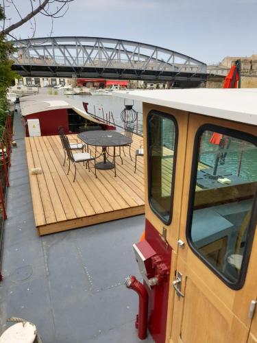 una terrazza in legno con tavolo e sedie su una barca di Péniche Chopine a Beaucaire