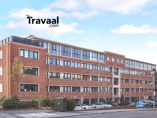 Travaal.©om - 2 Bed Serviced Apartment Farnborough في فارنبورو: مبنى من الطوب الأحمر مع سيارات متوقفة في موقف للسيارات