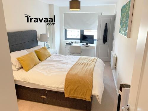 1 dormitorio con cama con almohadas amarillas y escritorio en Travaal.©om - 2 Bed Serviced Apartment Farnborough, en Farnborough