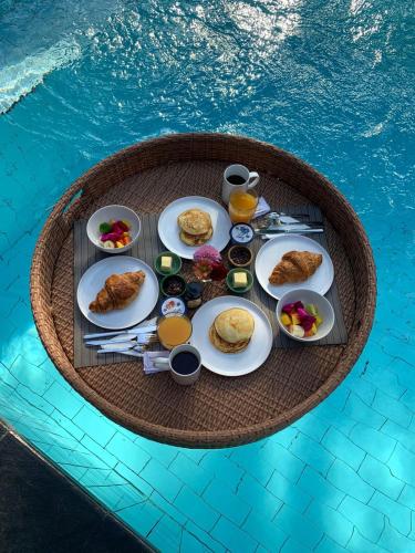 une table avec de la nourriture et des boissons dans une piscine dans l'établissement Villa Vana, Sitara Villa Group, à Seminyak