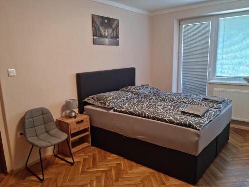 a bedroom with a bed and a chair and a window at Ubytovanie Na Hlavnej in Strekov