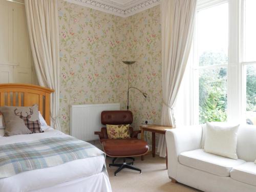 a bedroom with a bed and a chair and a window at Allerton House in Jedburgh