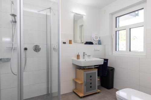 a white bathroom with a sink and a shower at Ferienwohnung am Schloßpark in Bad Berleburg