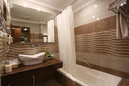 een badkamer met een wastafel, een bad en een spiegel bij The Imperial Kushinagar in Kushinagar