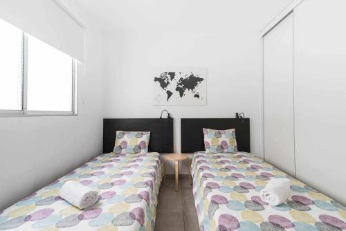 Habitación con 2 camas individuales y paredes blancas. en Piso en primera linea con vistas directas al mar, en Melenara