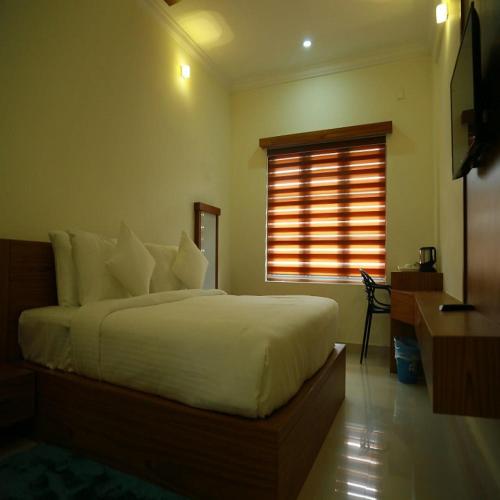a bedroom with a bed and a desk and a window at Sea Breeze Rest Inn in Kannur