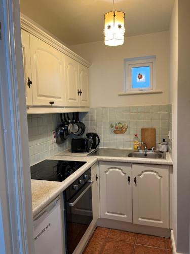 a kitchen with white cabinets and a sink at The Beach House in Lahinch