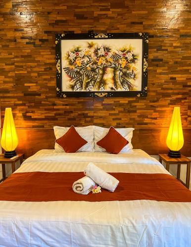 a bedroom with a large bed with two lamps at Bima Sakti Homestay Echo Beach Canggu in Canggu