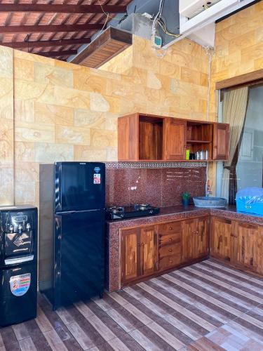 a kitchen with a black refrigerator and wooden cabinets at Bima Sakti Homestay Echo Beach Canggu in Canggu