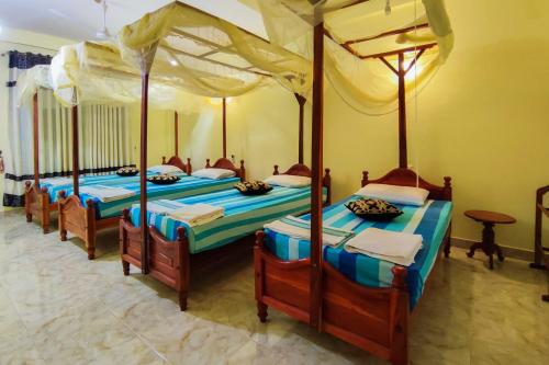 grupa czterech łóżek w pokoju w obiekcie La Safari Inn Tissamaharama w mieście Tissamaharama
