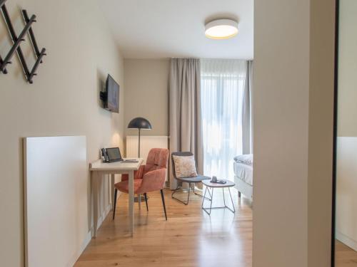 フォルカッハにあるHotel Tuchhausのデスク、椅子、ベッドが備わる客室です。