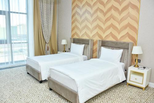 two beds in a hotel room with white sheets at Ramada by Wyndham Turkistan in Türkistan